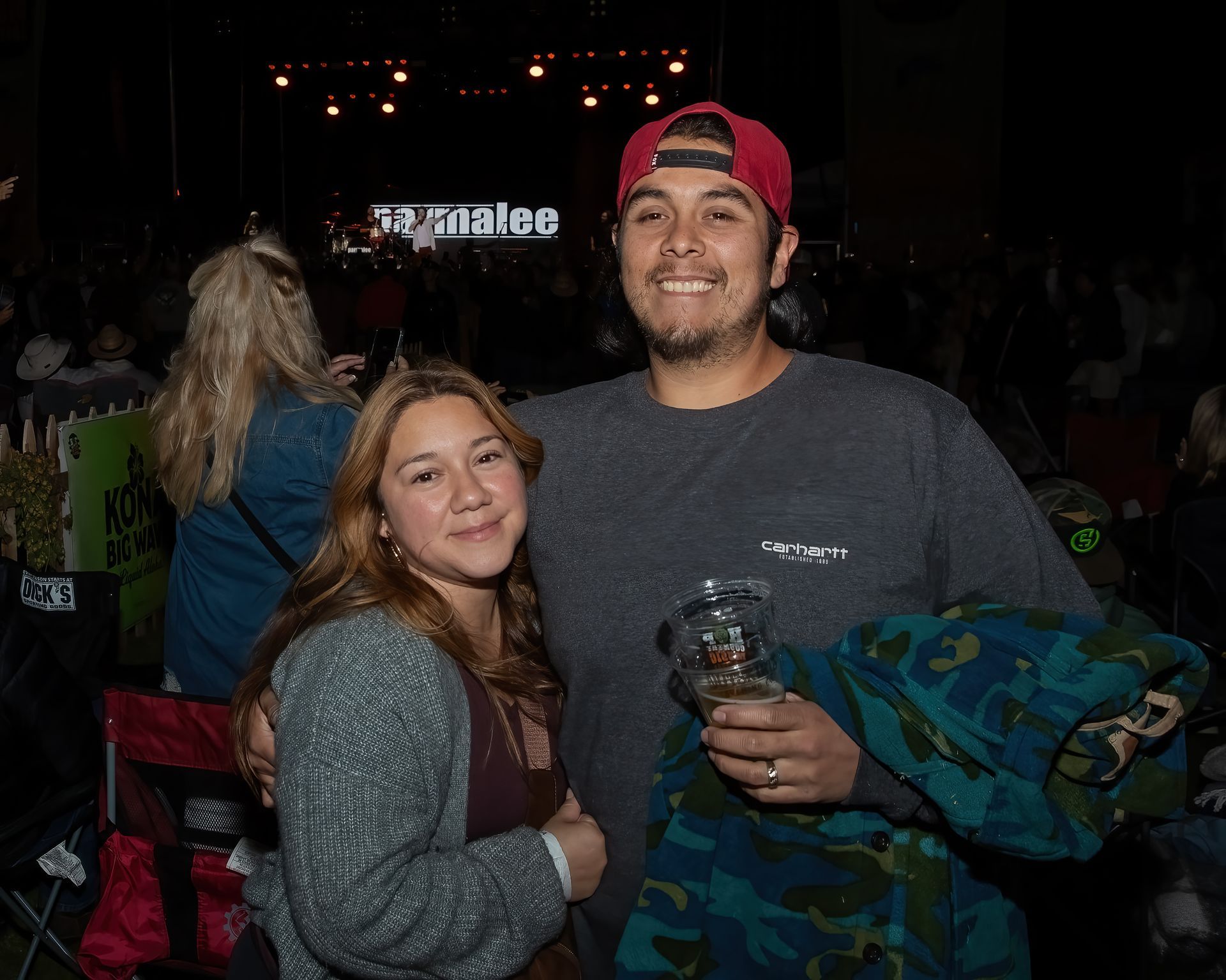 A man and a woman are posing for a picture at a concert.