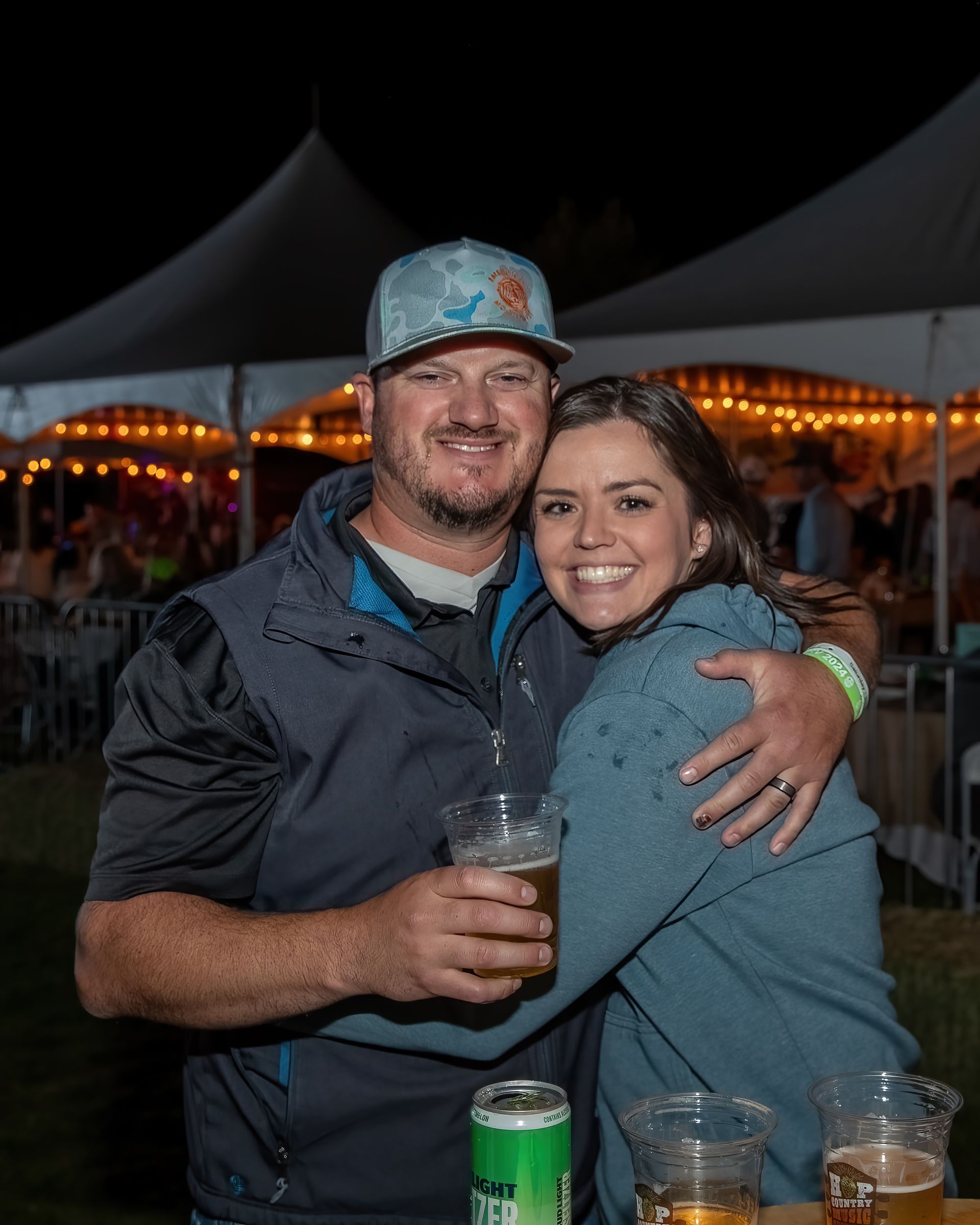 A man and a woman are posing for a picture while holding beer.