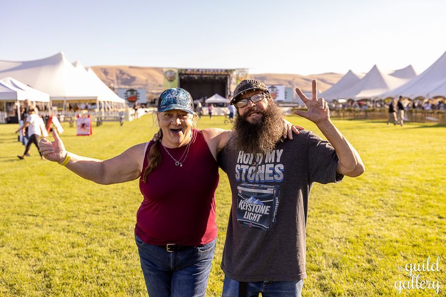 A man and a woman are posing for a picture in a field.