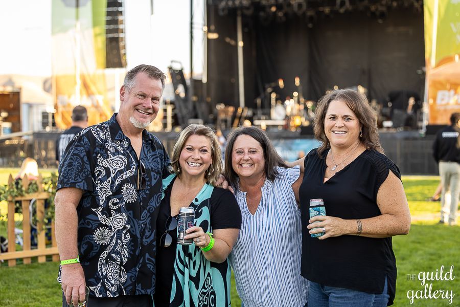 A group of people are posing for a picture in front of a stage at a concert.