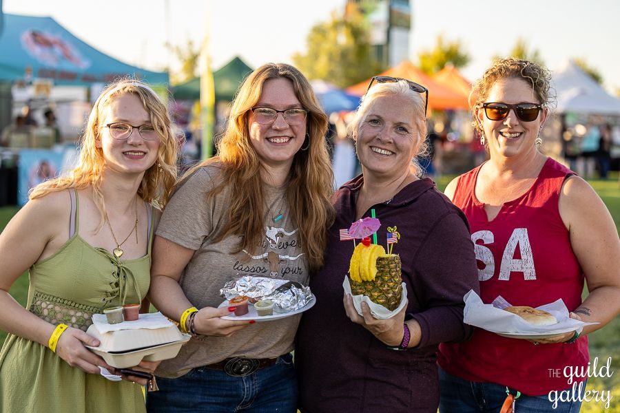 A group of women are standing next to each other holding plates of food.