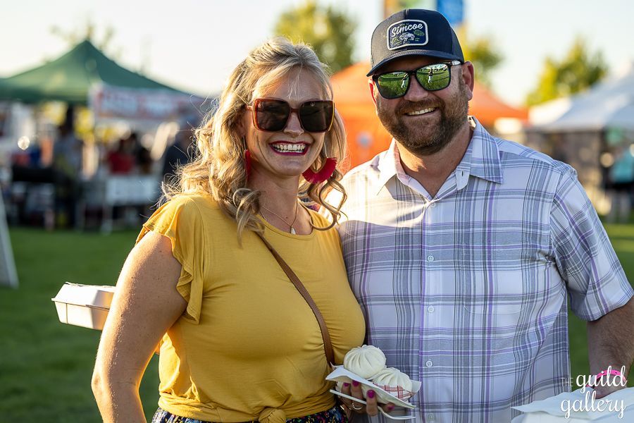 A man and a woman are posing for a picture at a festival.