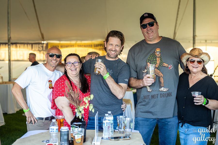 A group of people are standing around a table holding drinks.