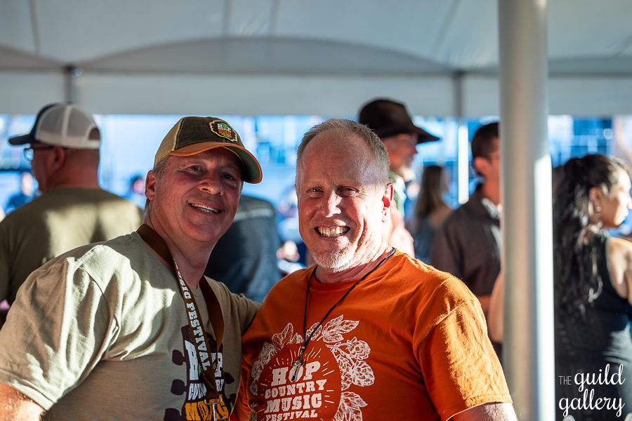 Two men are posing for a picture under a tent.