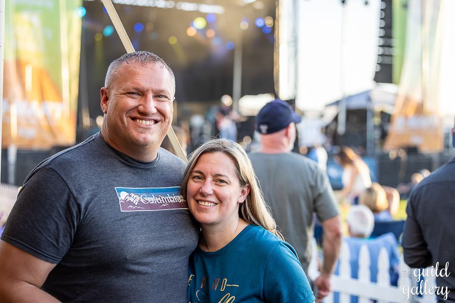A man and a woman are posing for a picture at a concert.