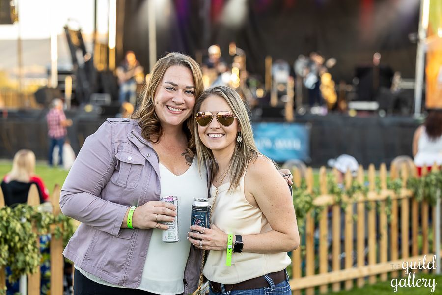 Two women are posing for a picture at a concert.
