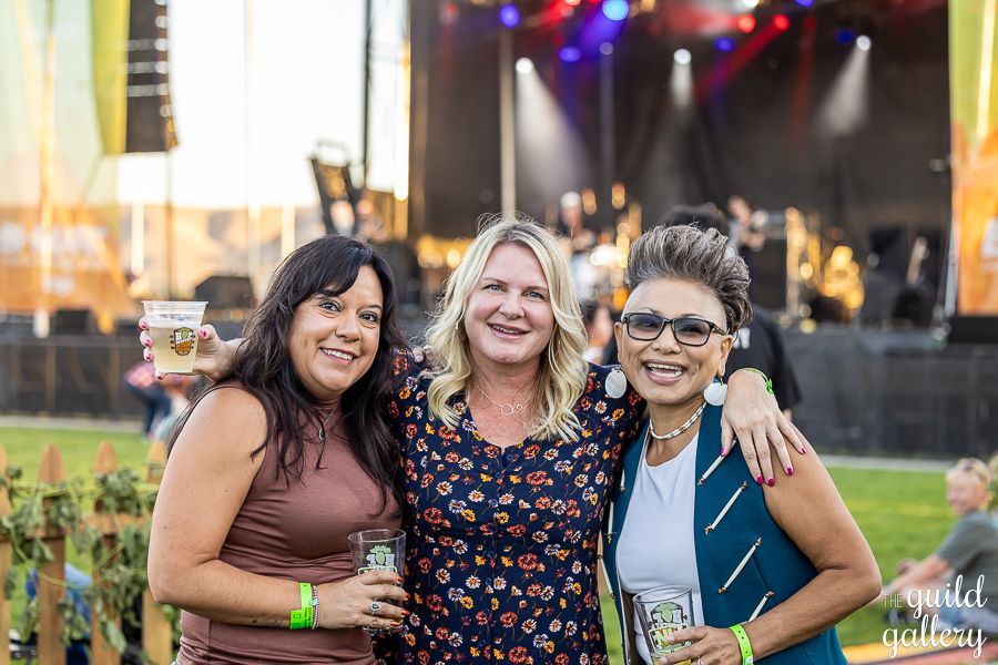 Three women are posing for a picture at a concert.