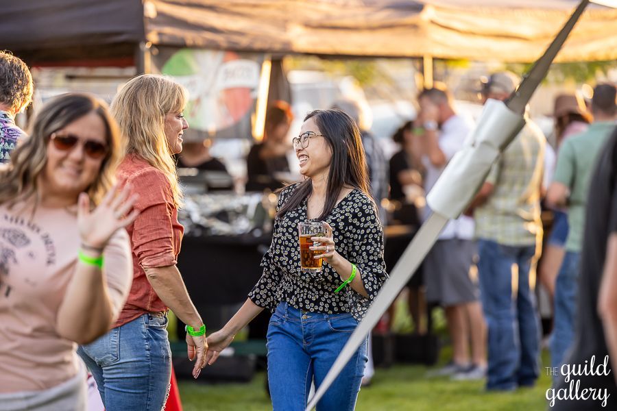 A group of people are standing in a field holding hands and drinking beer.