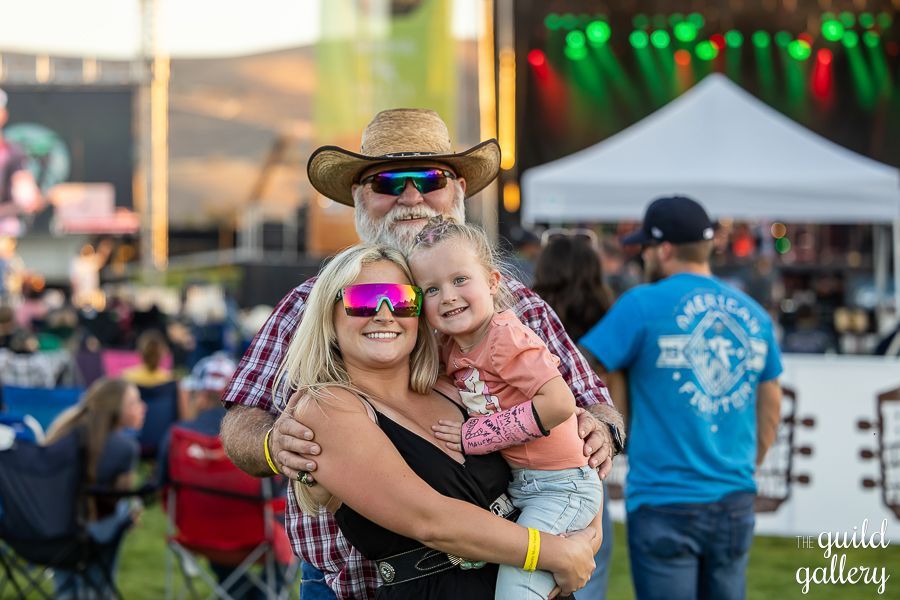 A man and woman are holding a little girl at a concert.
