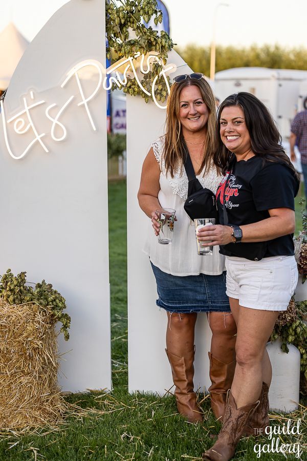 Two women are standing next to each other in front of a neon sign.