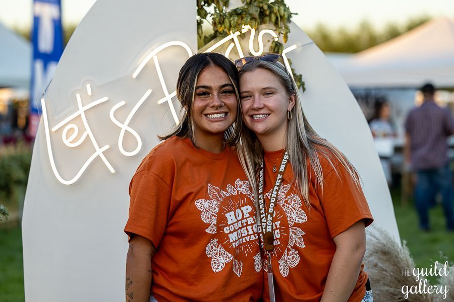Two women are posing for a picture in front of a neon sign.