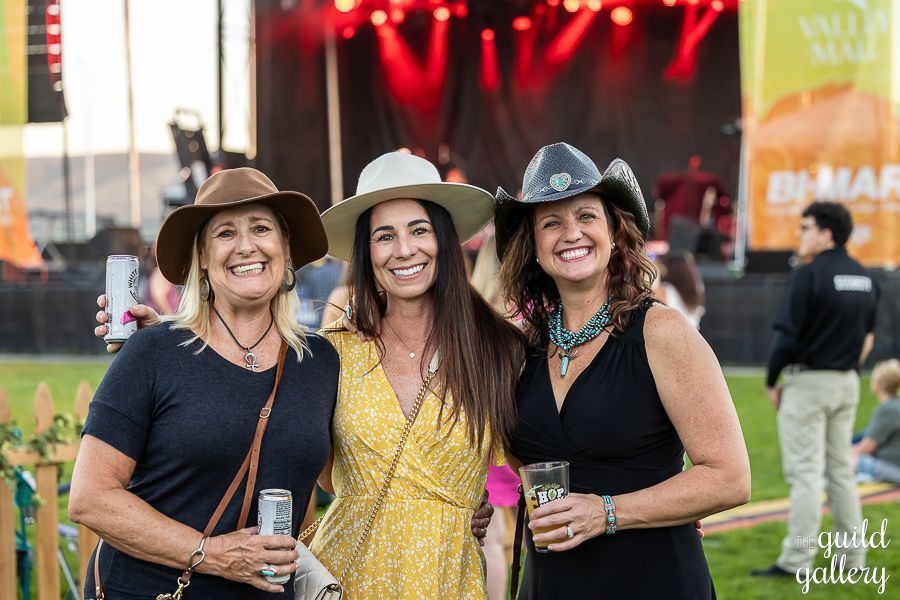 Three women wearing cowboy hats are posing for a picture at a concert.