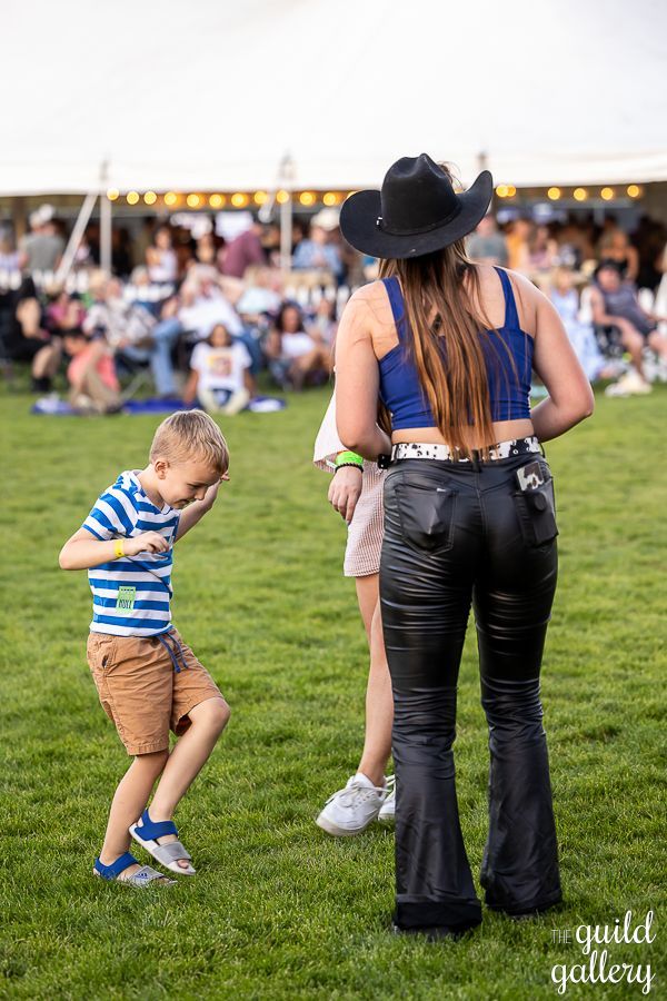 A woman in a cowboy hat is standing next to a boy in a field.