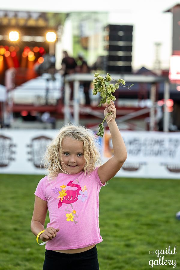 A little girl is holding a bunch of hops in her hand.