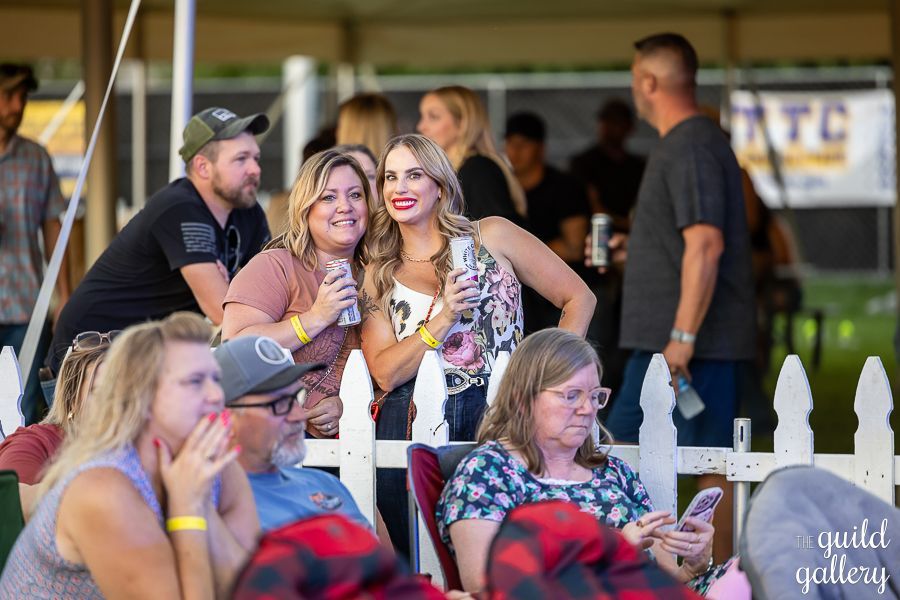 A group of people are sitting in front of a white picket fence.