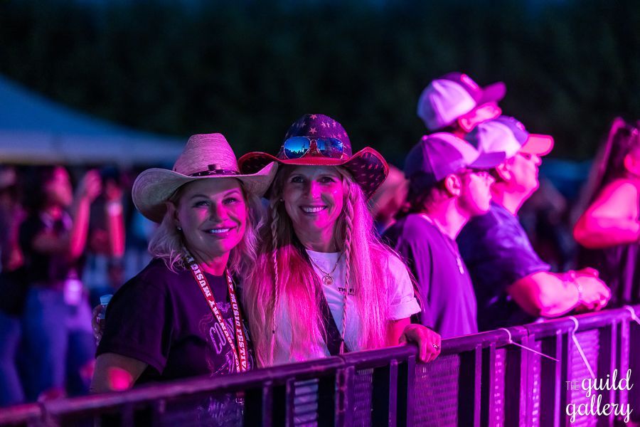 Two women in cowboy hats are standing next to each other at a concert.