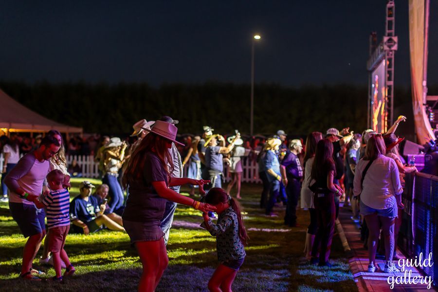 A group of people are dancing in a field at night.