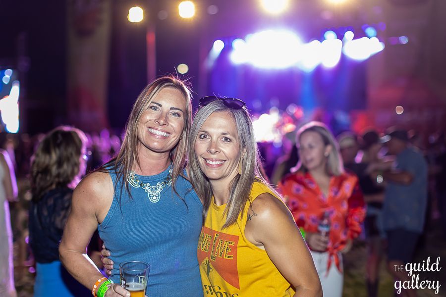 Two women are posing for a picture at a concert.