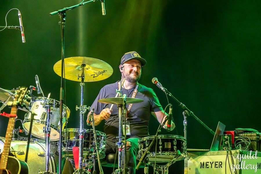 A man is playing drums on a stage in front of a microphone.