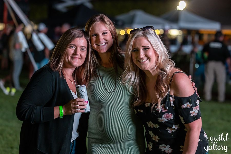 Three women are posing for a picture together at a concert.