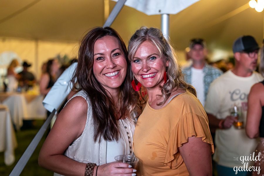 Two women are posing for a picture in front of a tent.