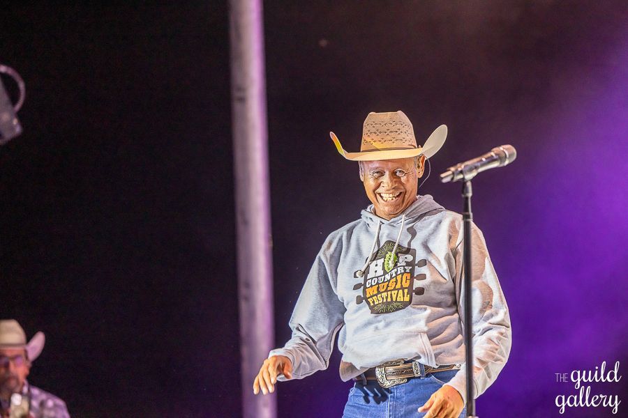 A man in a cowboy hat is singing into a microphone on a stage.