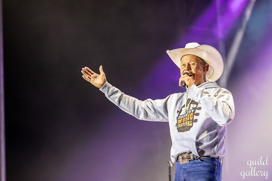 A man in a cowboy hat is singing into a microphone on a stage.