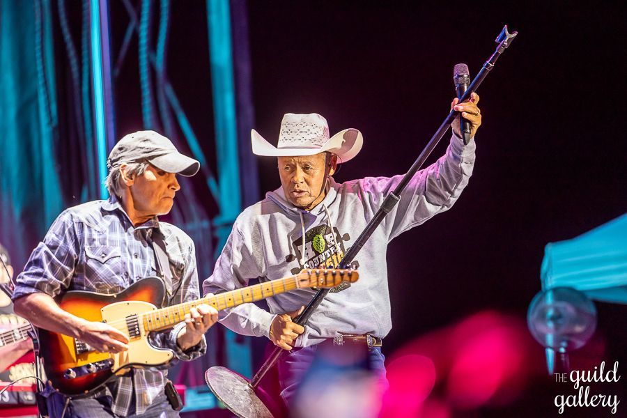 Two men are playing guitars and singing on a stage.