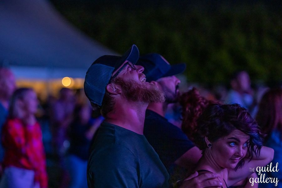 A man with a beard is looking up at the sky at a concert.