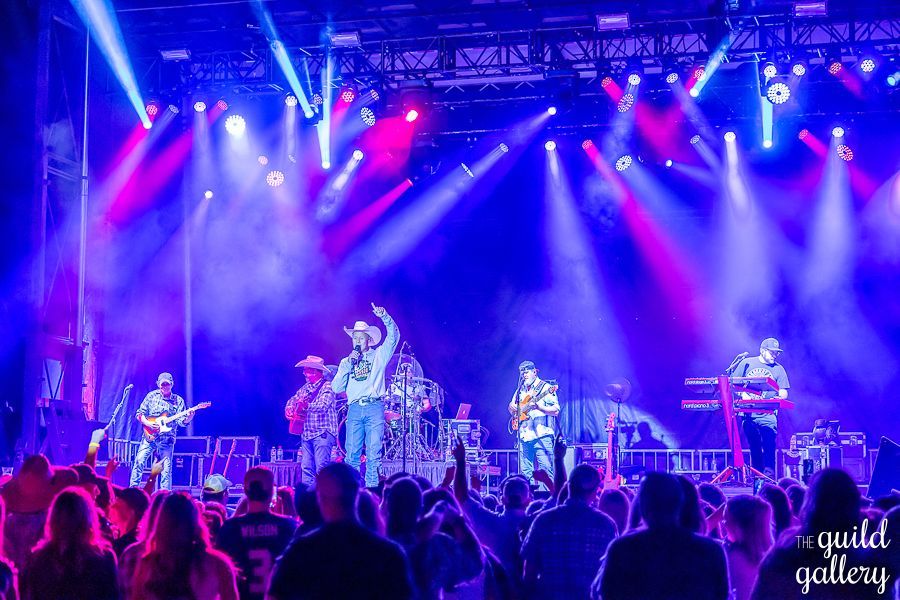 A group of people are standing in front of a stage with purple lights.