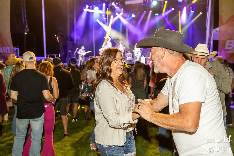 A man in a cowboy hat is dancing with a woman at a concert.