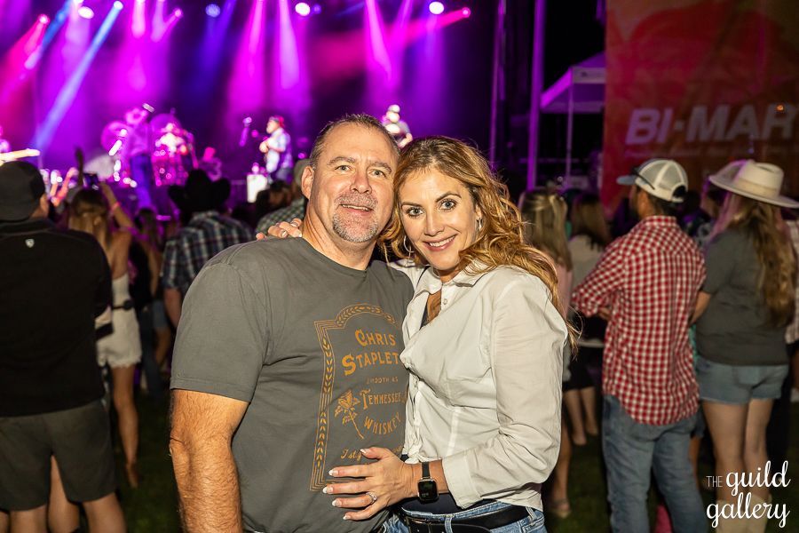 A man and a woman are posing for a picture at a concert.