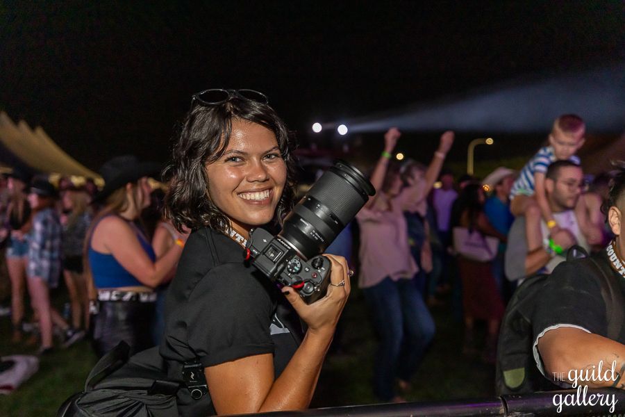 A woman is holding a camera in front of a crowd of people.