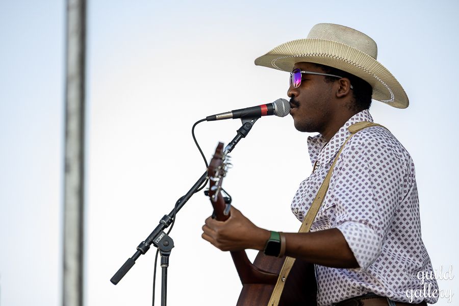 A man in a cowboy hat is singing into a microphone while playing a guitar.