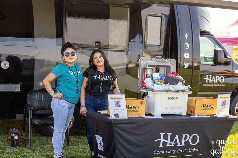 Two women are standing next to a table in front of a van.