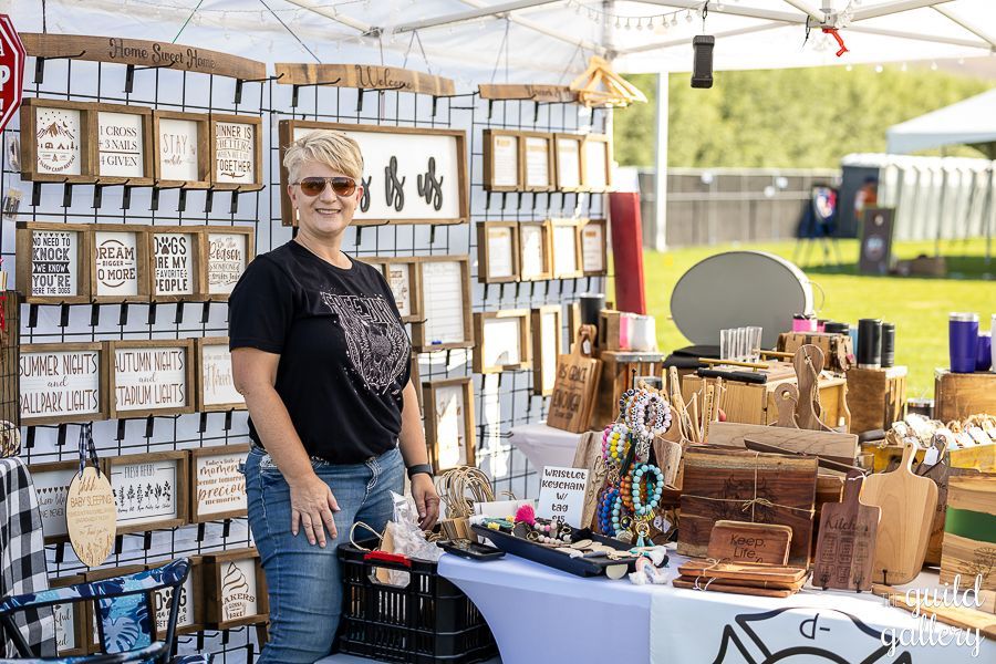 A woman is standing in front of a table at a craft fair.