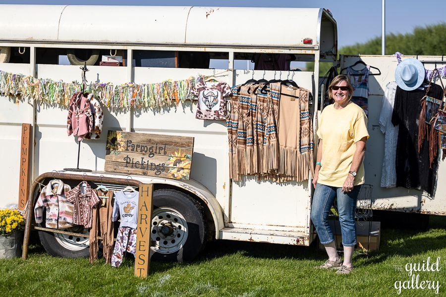 A woman is standing in front of a horse trailer.