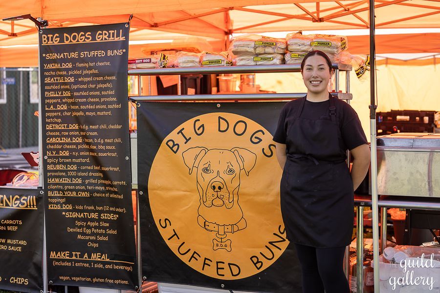 A man standing in front of a big dogs stuffed buns sign