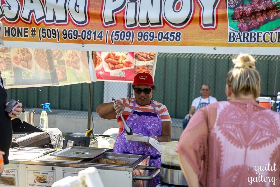 A woman is cooking food in front of a sign that says sang pinoy