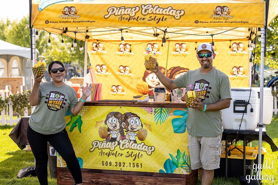 A man and a woman are standing in front of a pineapple stand.