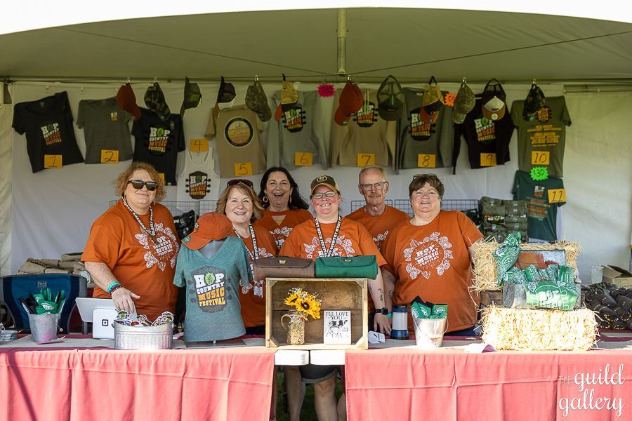 A group of people standing behind a table with shirts on it.