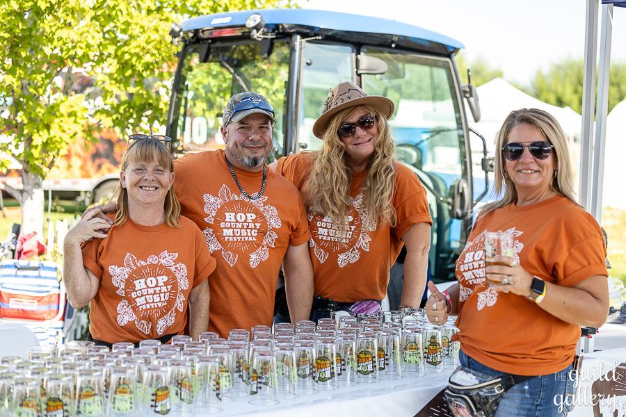 A group of people are standing around a table filled with glasses.