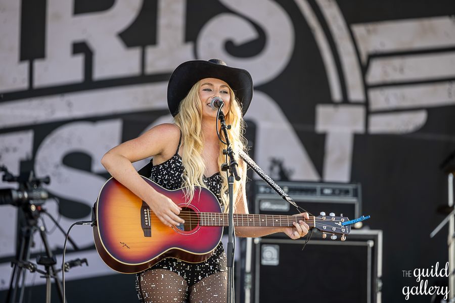 A woman is playing a guitar and singing into a microphone.