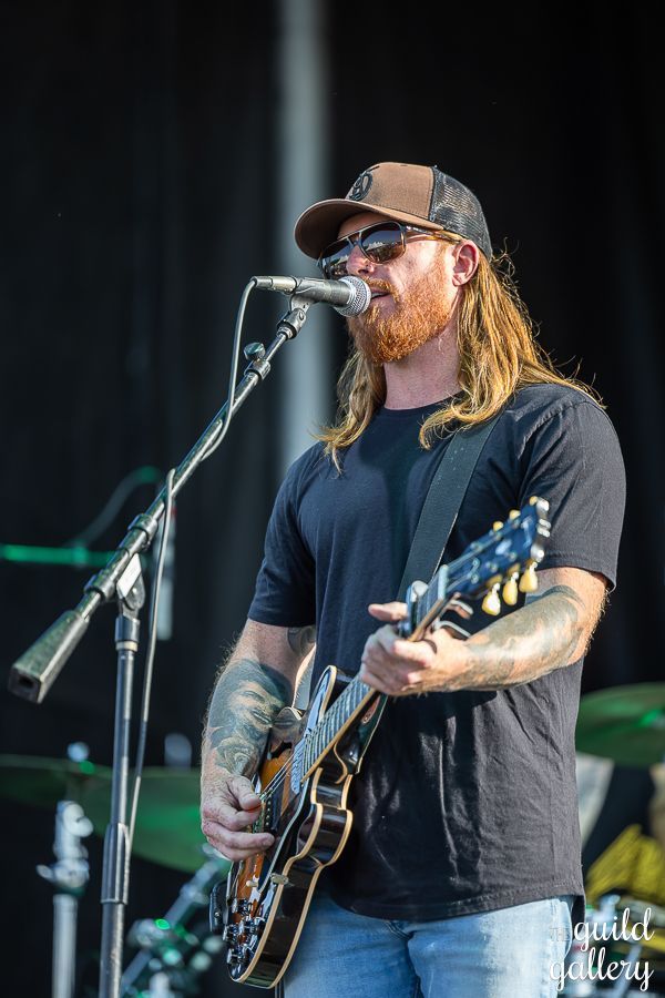 A man with long hair is playing a guitar and singing into a microphone.