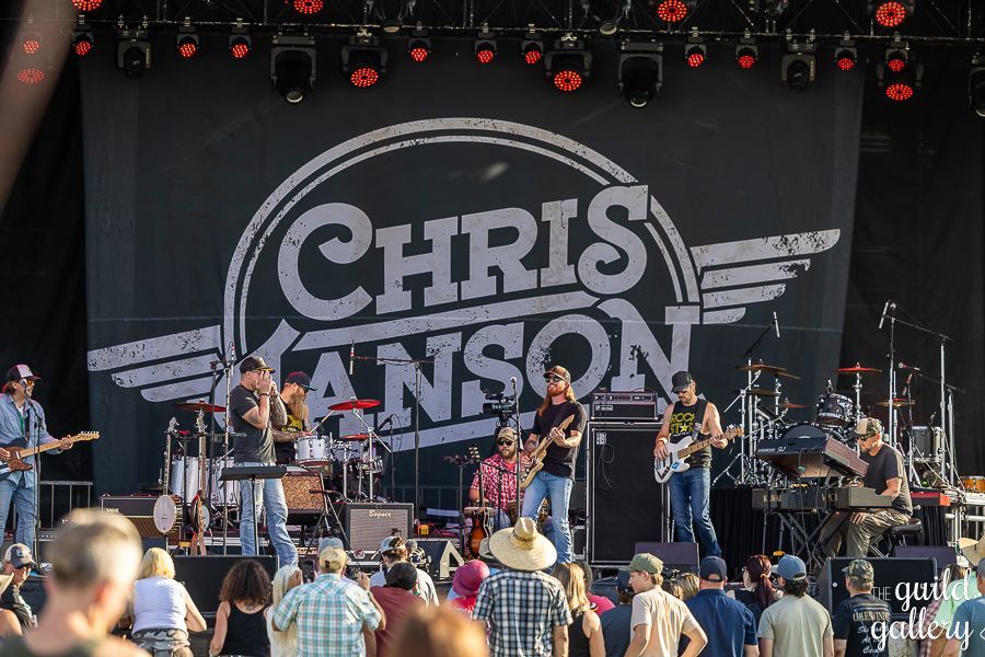 A group of people are standing in front of a stage with chris canson written on it.