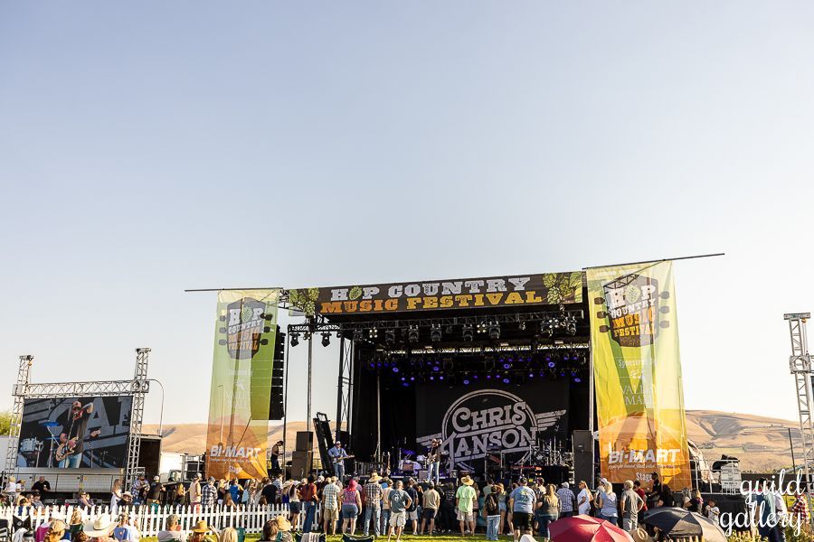 A crowd of people are gathered in front of a stage at a country music festival