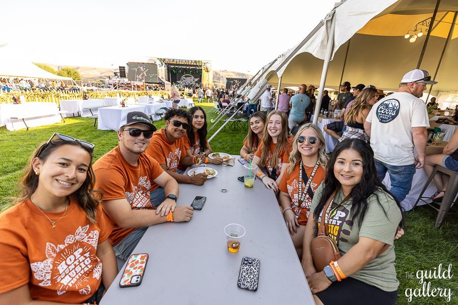 A group of people are sitting at a long table under a tent.