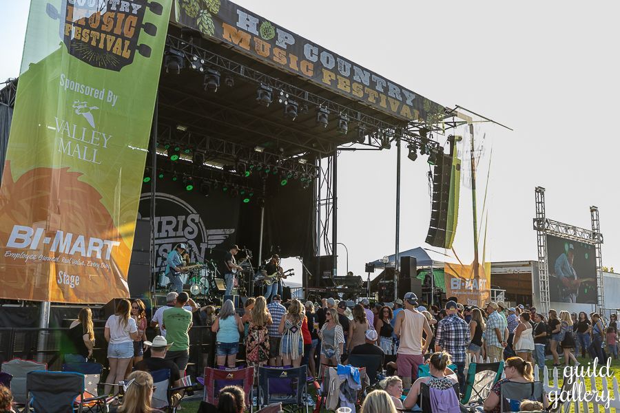 A group of people are standing in front of a stage at a music festival.