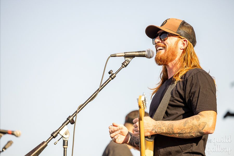A man is singing into a microphone while playing a guitar.