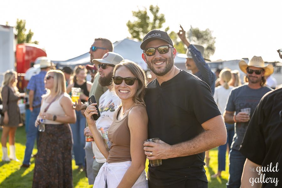 A man and a woman are posing for a picture in front of a crowd at a festival.